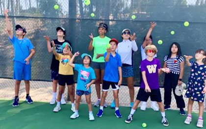 group of kids with tennis racquets and tennis balls